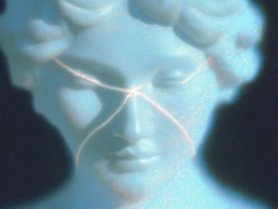 A glowing pale blue classical marble face emerging from darkness, crossed by faint glowing orange lines like threads