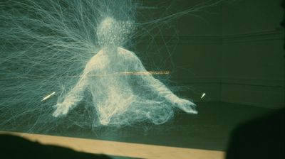 From a low angle, a seated blue-white wireframe figure with a head of dense, unreadable text; thousands of fine filaments erupt from its back and head like a neural aurora across a dim green room. A faint amber line crosses the chest.