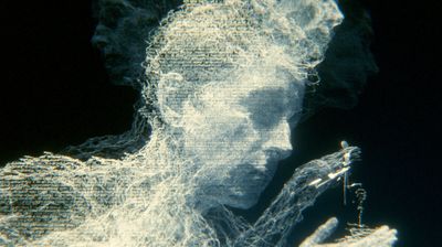 An afterimage dissolving into horizontal scanlines: a face in profile and shoulders made of white-blue threads of text break apart against black, a hand at lower right still holding a small key-like tool.