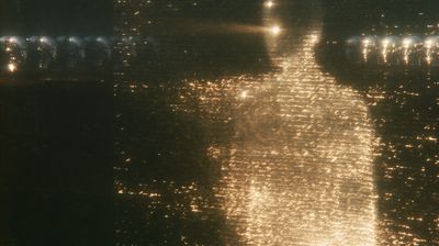 A giant ember-orange figure formed of burning text strides forward through darkness, rows of chrome androids watching from both sides.