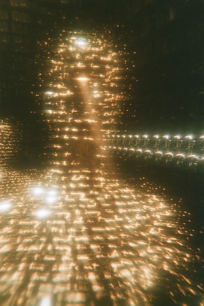 A walking translucent figure with tree-ring circles glowing in its chest, chrome androids in rows behind and words reflected in the floor.