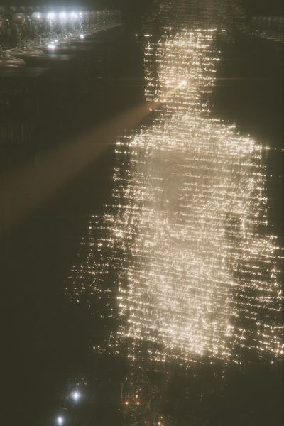 A towering robed giant made of glowing words looms over robots seated like judges, a small human silhouette standing at its base.