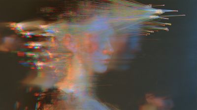 A pale face in profile dissolves into lines of text and colored light, with bright threads fanning to the upper right.